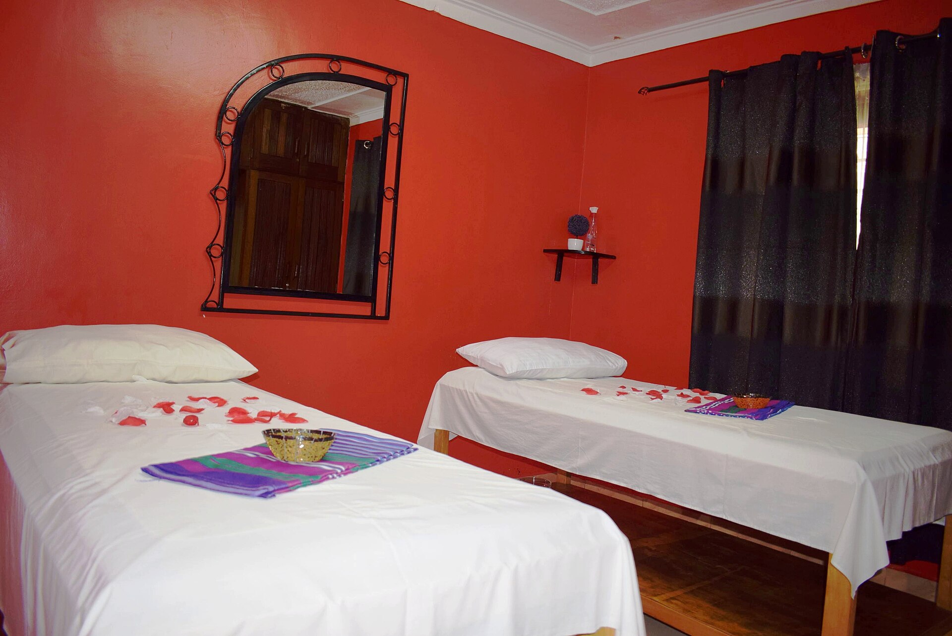 Two massage beds with white sheets and folded towels in a calm red room